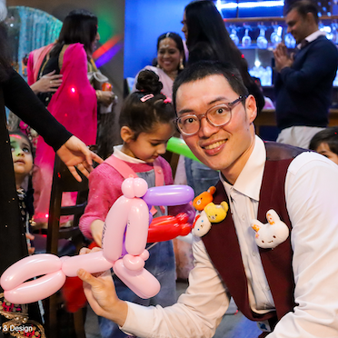 balloon twisting artist with his unicorn balloon animal at a birthday party