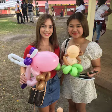 unicorn and money balloon animals with two happy girls