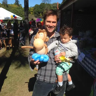 a happy parent with his kids holding a monkey balloon twisting animal